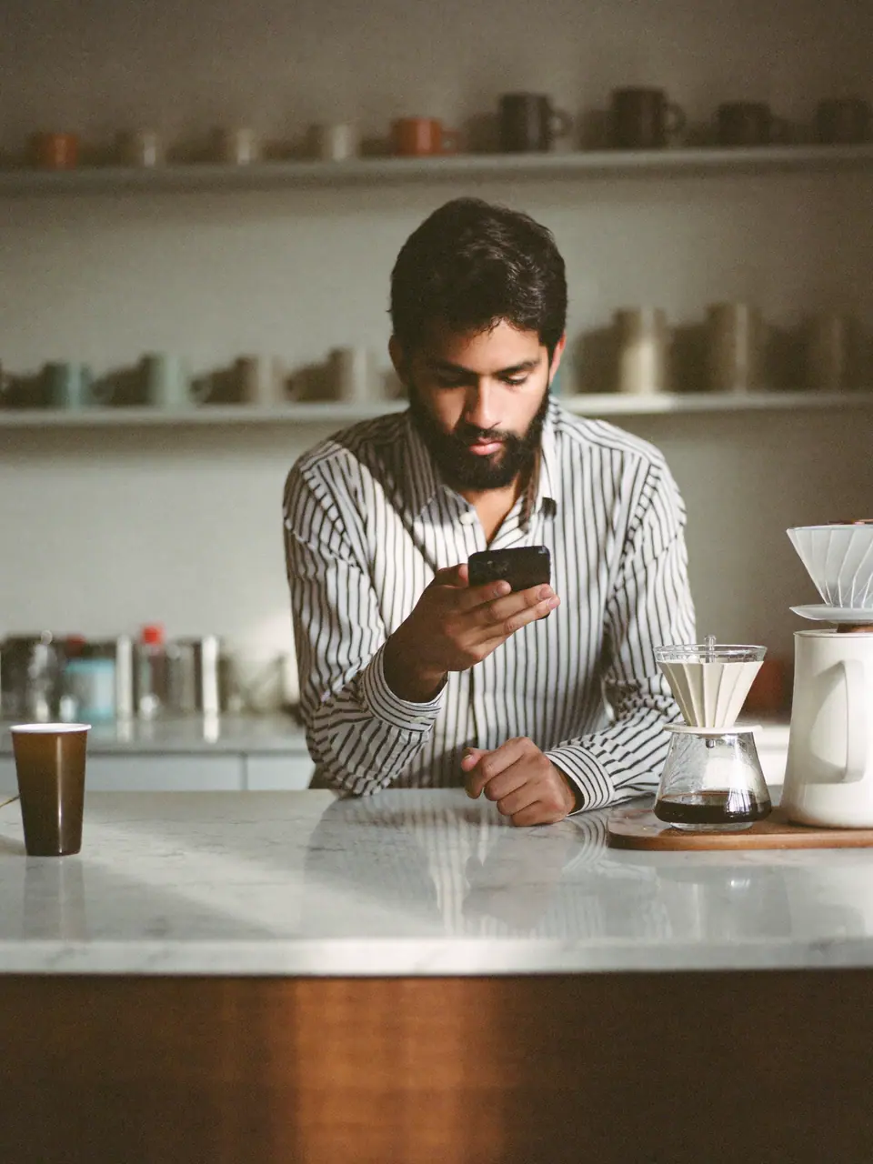 A café owner checking his phone behind a marble counter